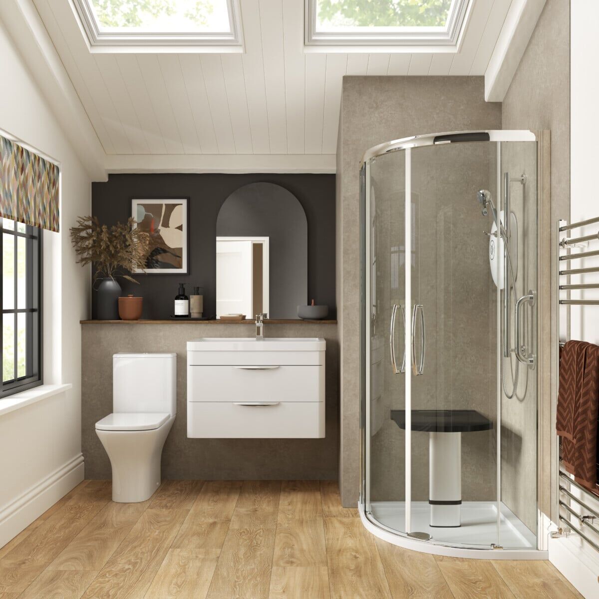 Modern bathroom with wood flooring, corner curved glass shower, white wall-mounted sink cabinet, toilet, towel rail, and skylights. Decor includes a vase with dried plants and framed art above the sink.
