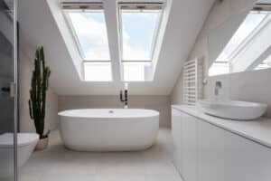 Freestanding bath in white bathroom with skylight