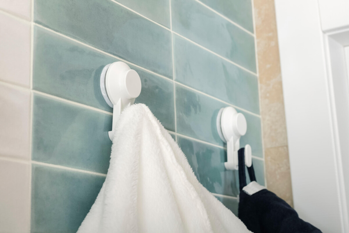 Close-up of a white terrycloth bathrobe hanging on a white hook in the bathroom.