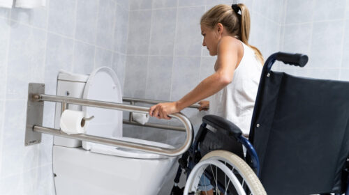 Blonde girl holding on to rails at the toilet trying to get up