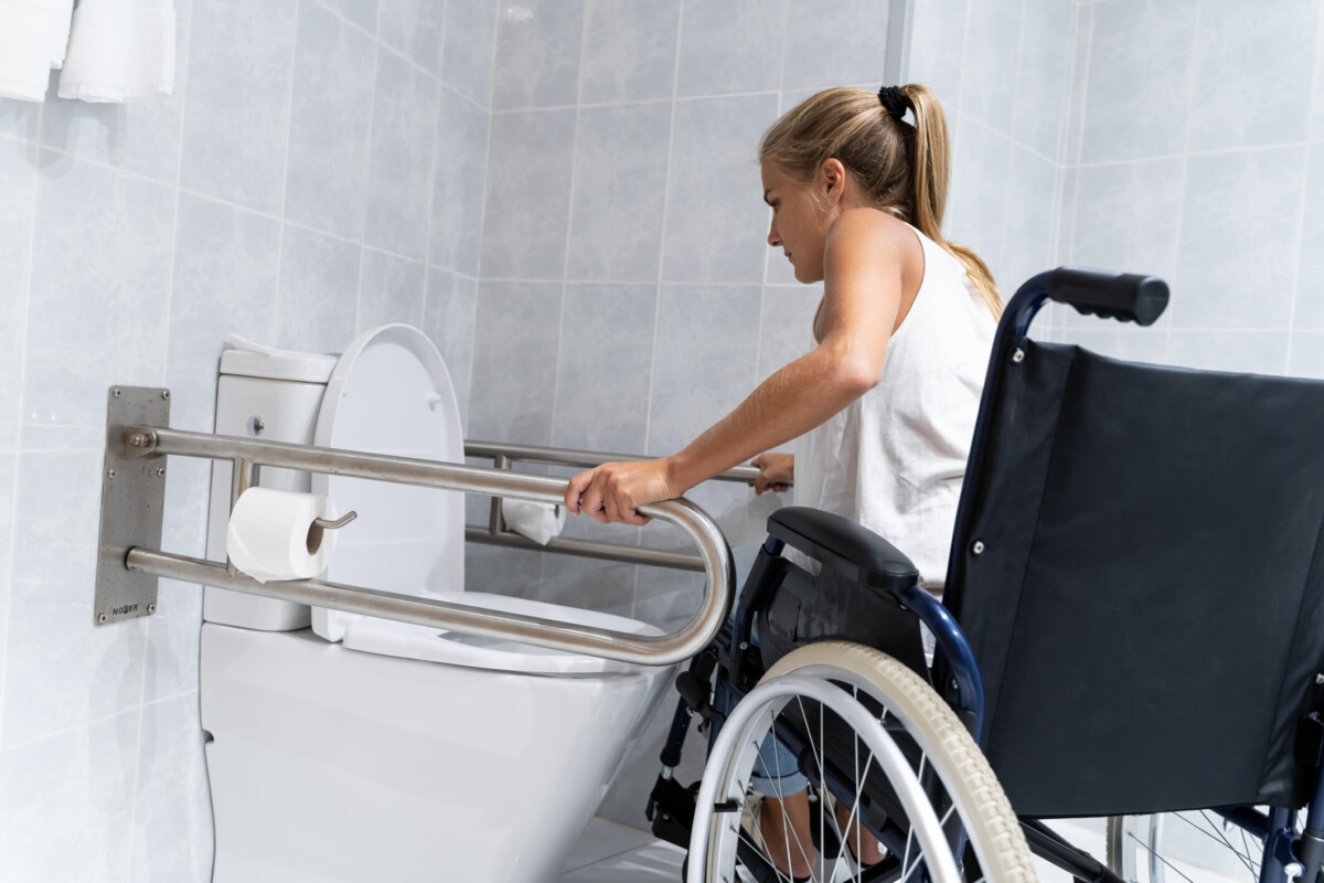 Blonde girl holding on to rails at the toilet trying to get up