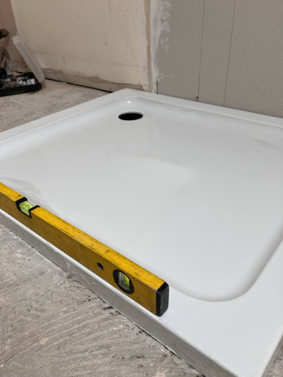 Shower Tray laid on a suspended floor with spirit level checking it is flat.